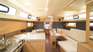 Een ruimtelijk ingerichte camper met een kitchenette, een eethoek en een slaapplaats.
