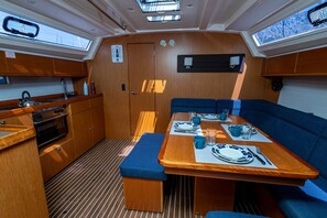 A compact galley with a stove, oven, and sink; a dining table set with plates, glasses, and cutlery; and a bench.