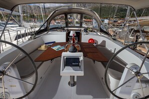 Das Deck eines Bootes mit Steuer, Steuermannstand und Blick auf den Hafen.