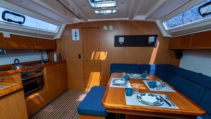 A compact galley with a stove, oven, and sink; a dining table set with plates, glasses, and cutlery; and a bench.