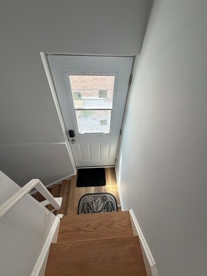 A staircase leading to a door with a window, a doormat, and a small rug.