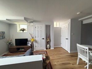 A living room with a sofa, a TV, and a coffee table. There are two doors leading to other rooms.