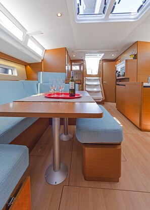 A modern interior with a dining area featuring a table, chairs, and a bench. - Sun-Kissed Sailing Adventure in the Saronic Islands (Laurium)
