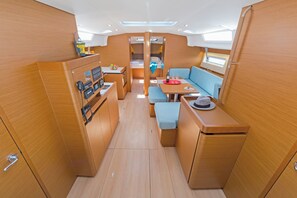 A compact, well-lit interior with a central seating area, a control panel, and a small kitchenette.