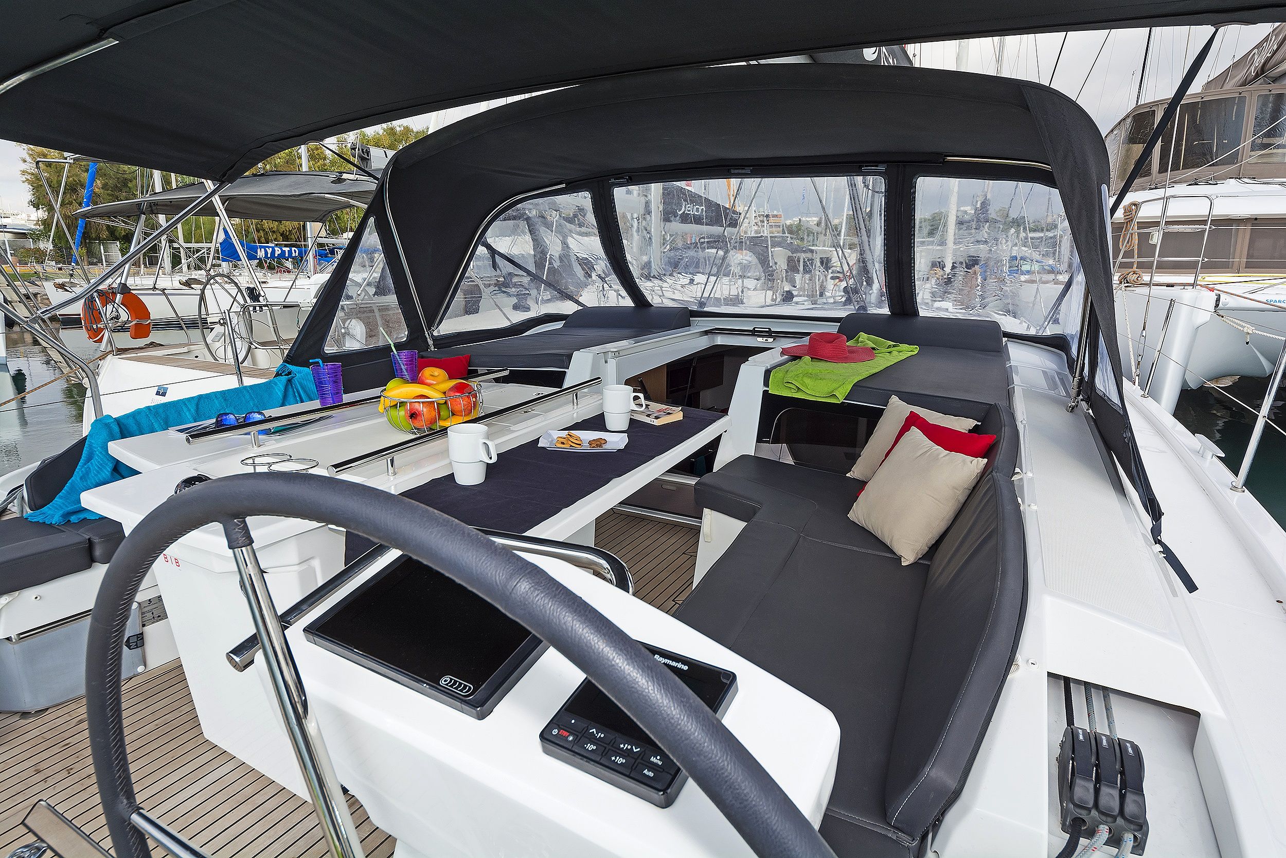 A boat's interior with a dining area, a steering wheel, and a control panel.