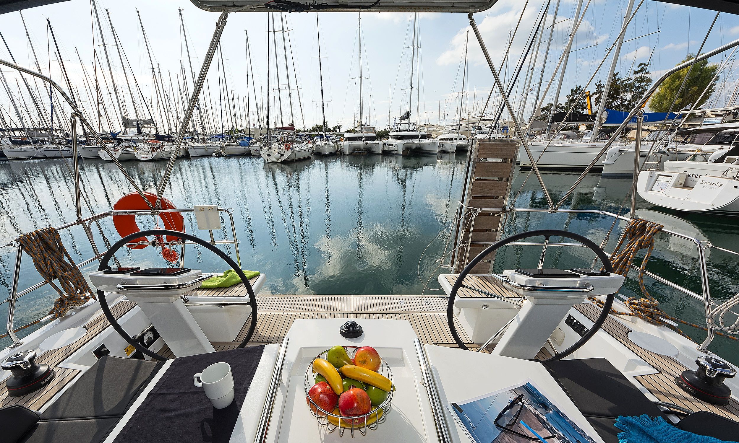 A boat deck with a steering wheel, a life preserver, and a fruit bowl.