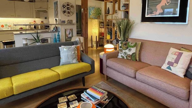 A living room with a grey sofa, a pink sofa, and a coffee table with books and a mug. - Stylish Loft - Amazing Views (Geneva)