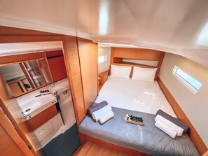 Una habitación compacta con cama, una mesita pequeña, un espejo y estantería empotrada.