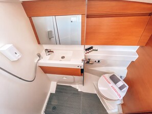 A compact bathroom with a white sink, a mirror, and a toilet. - Sun-Kissed Sailing Adventure in Islas Sarónicas (Alimos)