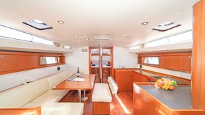 A compact, well-lit interior with a dining area, seating, and a kitchenette. - Sun-Kissed Sailing Adventure in Islas Sarónicas (Alimos)
