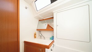 A bathroom with a wooden vanity, a sink, a mirror, and a towel rack. - Sun-Kissed Sailing Adventure in Islas Sarónicas (Alimos)
