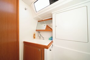 A bathroom with a wooden vanity, a sink, a mirror, and a towel rack. - Sun-Kissed Sailing Adventure in Islas Sarónicas (Alimos)