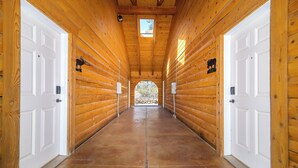 Un pasillo con paredes de madera, puertas blancas y vista al exterior.