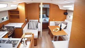 A compact galley with a stove, sink, and a small seating area with cushions. - Sun-Kissed Sailing Adventure in Islas Sarónicas (Alimos)