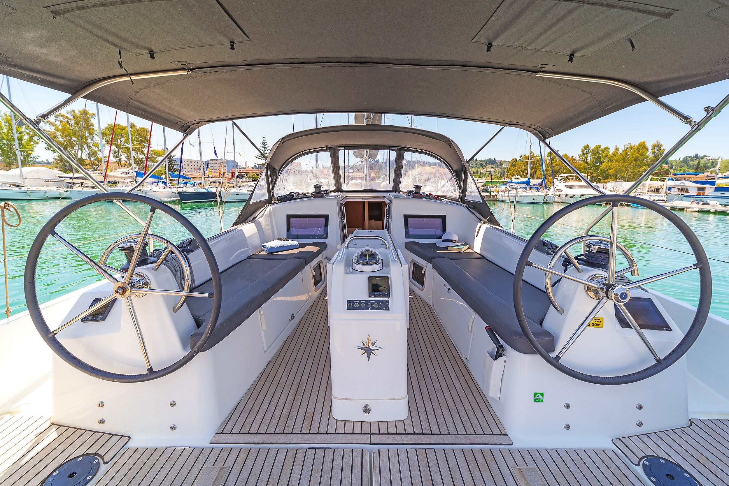 A boat's deck with a steering wheel, control panel, and seating area.