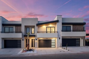 A modern two-story house with a garage, a balcony, and a well-lit entrance.