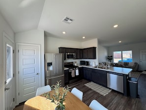 Una cocina moderna con electrodomésticos de acero inoxidable, armarios oscuros y una isla central.