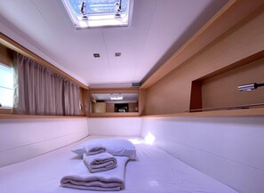 Ein kompakter, moderner Raum mit Bett, einem Fenster mit Vorhängen, einem Oberlicht und einer kleinen Küchenzeile.