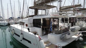 En vit yacht låg förtöjd vid en småbåtshamn med flera master, ett täckt däck och ett litet, öppet däck med sittplatser.