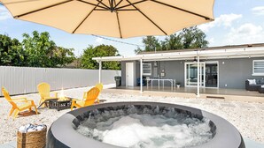 A hot tub with an umbrella, outdoor seating, and a building in the background. - Modern home with Jacuzzi/ Near Siesta Key Beach (Sarasota)