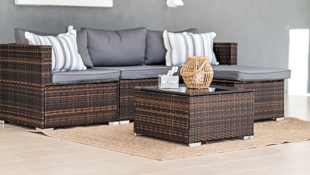 A sectional sofa with a woven base, a woven basket, and a striped pillow. - Modern home with Jacuzzi/ Near Siesta Key Beach (Sarasota)