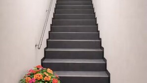 A staircase with a handrail and a flower arrangement at the bottom.