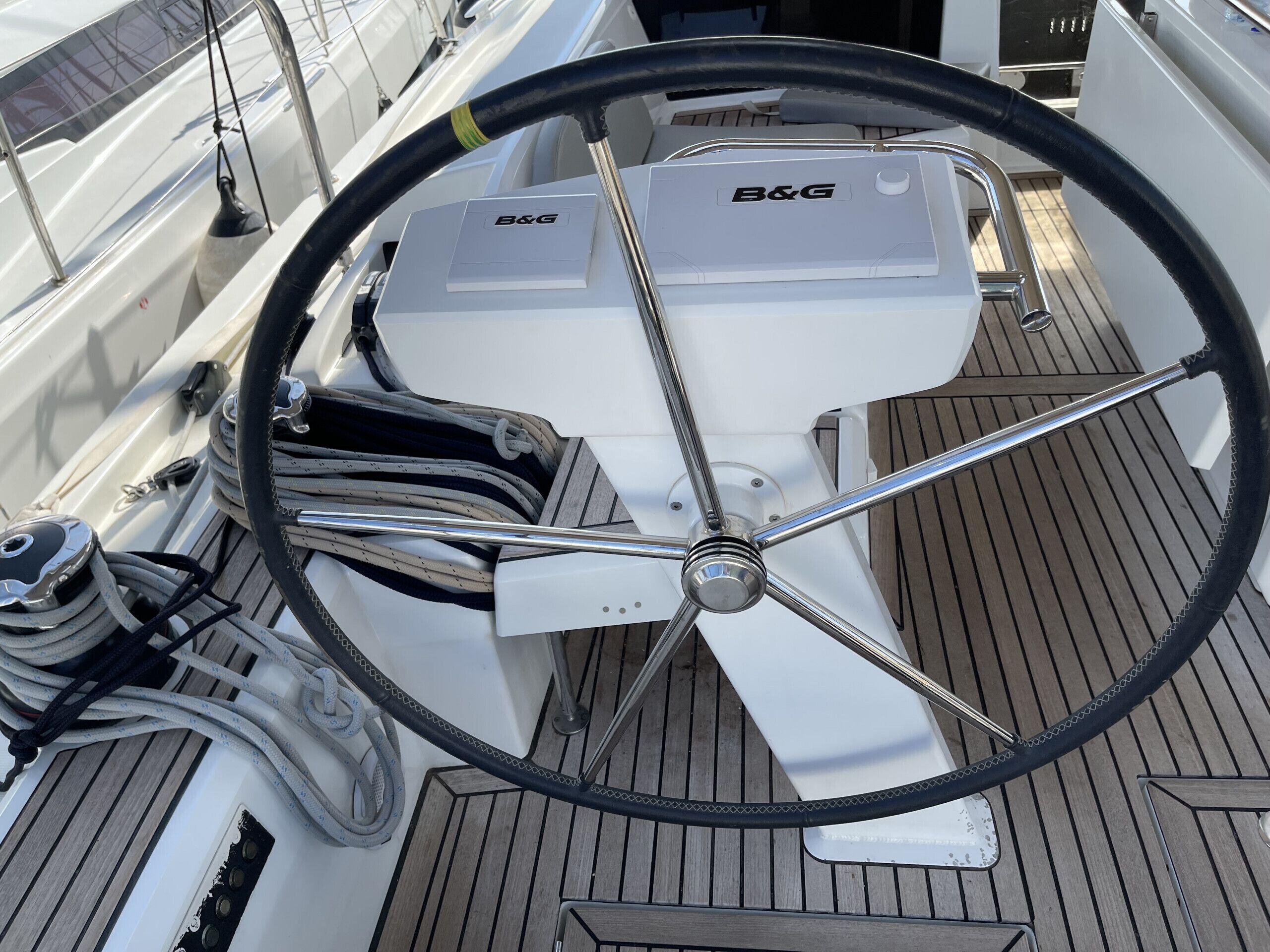 A boat's steering wheel, B&G logo, and a white engine.