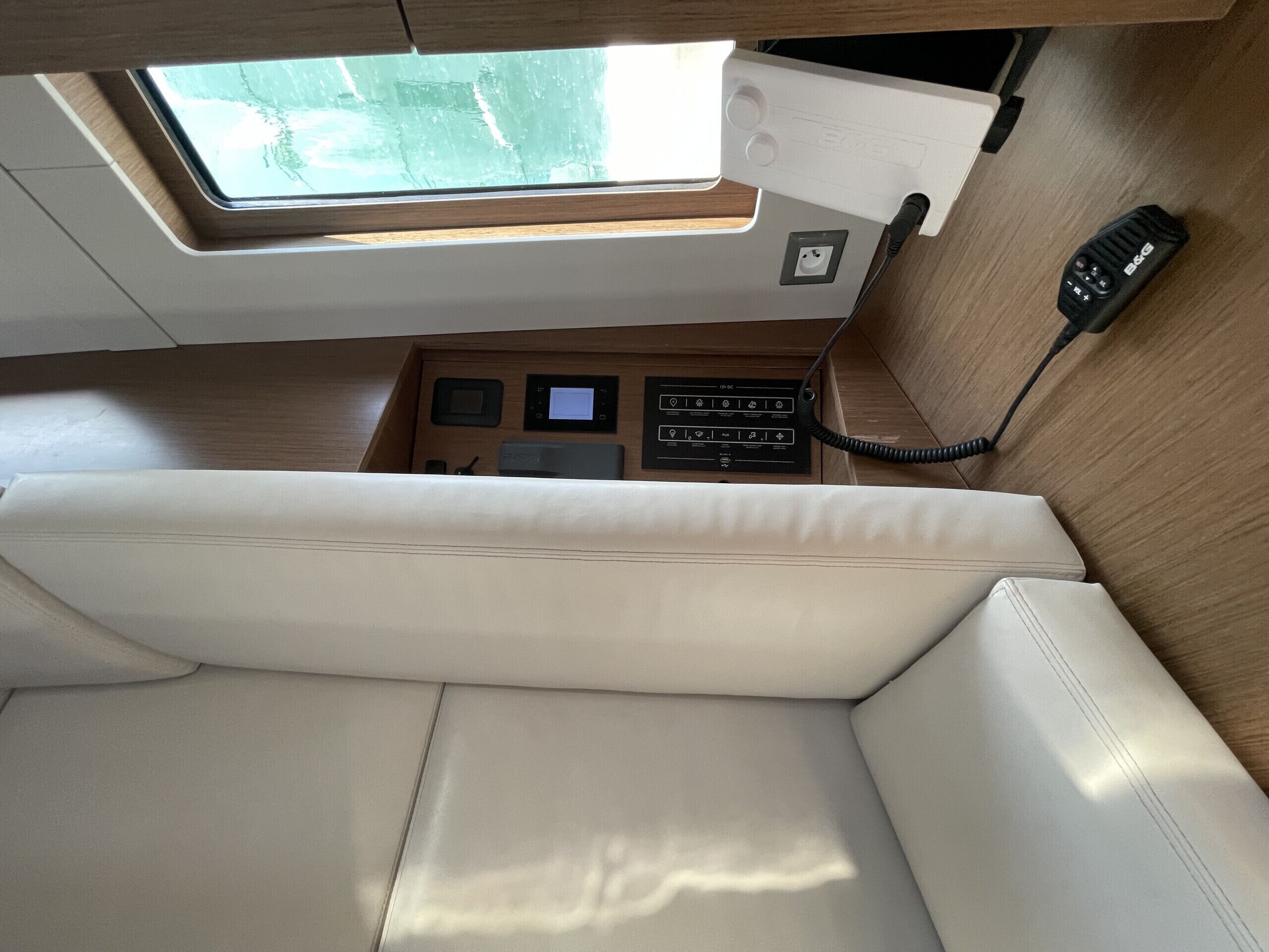 A cabin interior with a cushioned seating area, a control panel with various buttons and displays, and a window providing natural light.