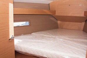 A compact, wooden interior with a single bed, a small window, and a door.