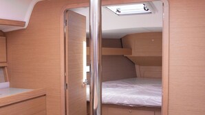 Un intérieur compact et bien aménagé, comprenant un lit superposé, un petit bureau et un meuble de rangement.