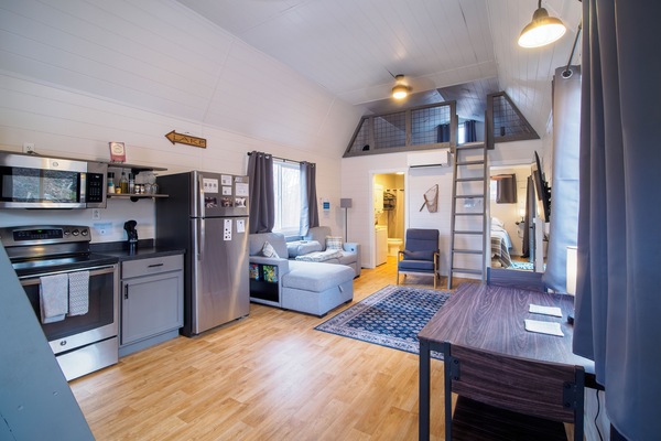 Open-concept kitchen/dining/living room. Living room features queen sofa bed