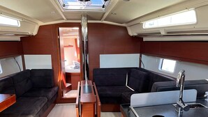 Een compact interieur met een centrale tafel, twee banken, een kleine kitchenette en een dakraam.