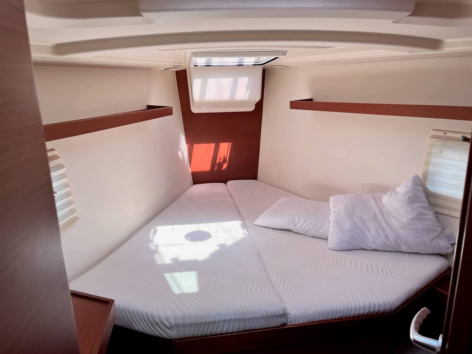 Een compact RV-interieur met een bed, een raam en een airconditioning.
