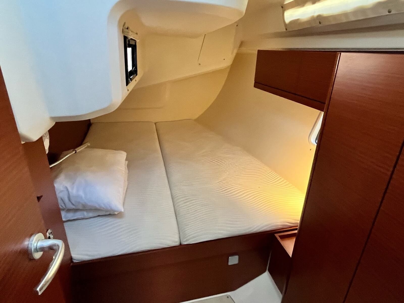 A compact cabin with a single bed, a small window, and a door with a handle.