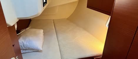 Une petite cabine comprenant un lit simple, une petite fenêtre et une porte dotée d’une poignée.