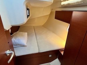 Uma cabana compacta com uma cama de solteiro, uma pequena janela e uma porta com maçaneta.