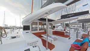 Ein Yachtdeck mit Sitzbereichen, einem Steuer und dem Schriftzug 'Jaison' auf einem Segel.