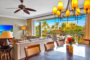 A hotel room with a balcony, a sofa, a dining table, and a ceiling fan. - Honua Kai 2 Free Rental Cars KBM Resorts Grand Suite 2 Units, 5 Bedrooms HK Ml-2645 (Kaanapali)