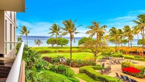 A hotel balcony with a view of the ocean, palm trees, and a well-maintained garden. - Honua Kai 3 Free Rental Cars KBM Resorts Grand Suite 3 Units, 8 Bedrooms HK Ml-2660 (Kaanapali)