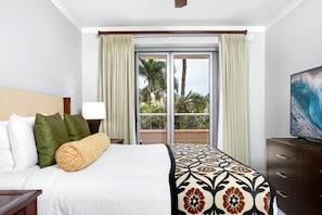 A hotel room with a bed, a nightstand, a TV, a window with curtains, and a view of palm trees. - Honua Kai 3 Free Cars KBM Resorts Front Alii Suite 3 Units, 6 Bedrooms HK Ml-3155 (Kaanapali)