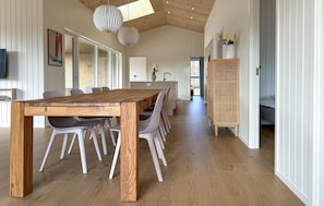 A modern interior with a wooden dining table, white chairs, a rattan sideboard, and a television mounted on the wall. - Gorgeous home in Sæby with WiFi (Sæby)