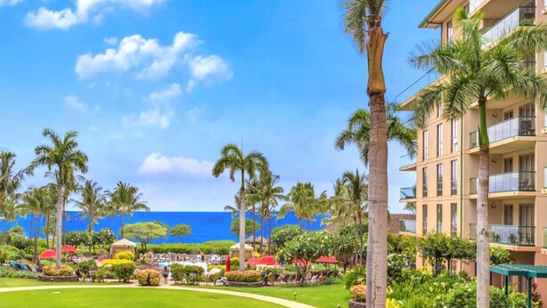 Un resort con zona de piscina, palmeras y vistas al océano.