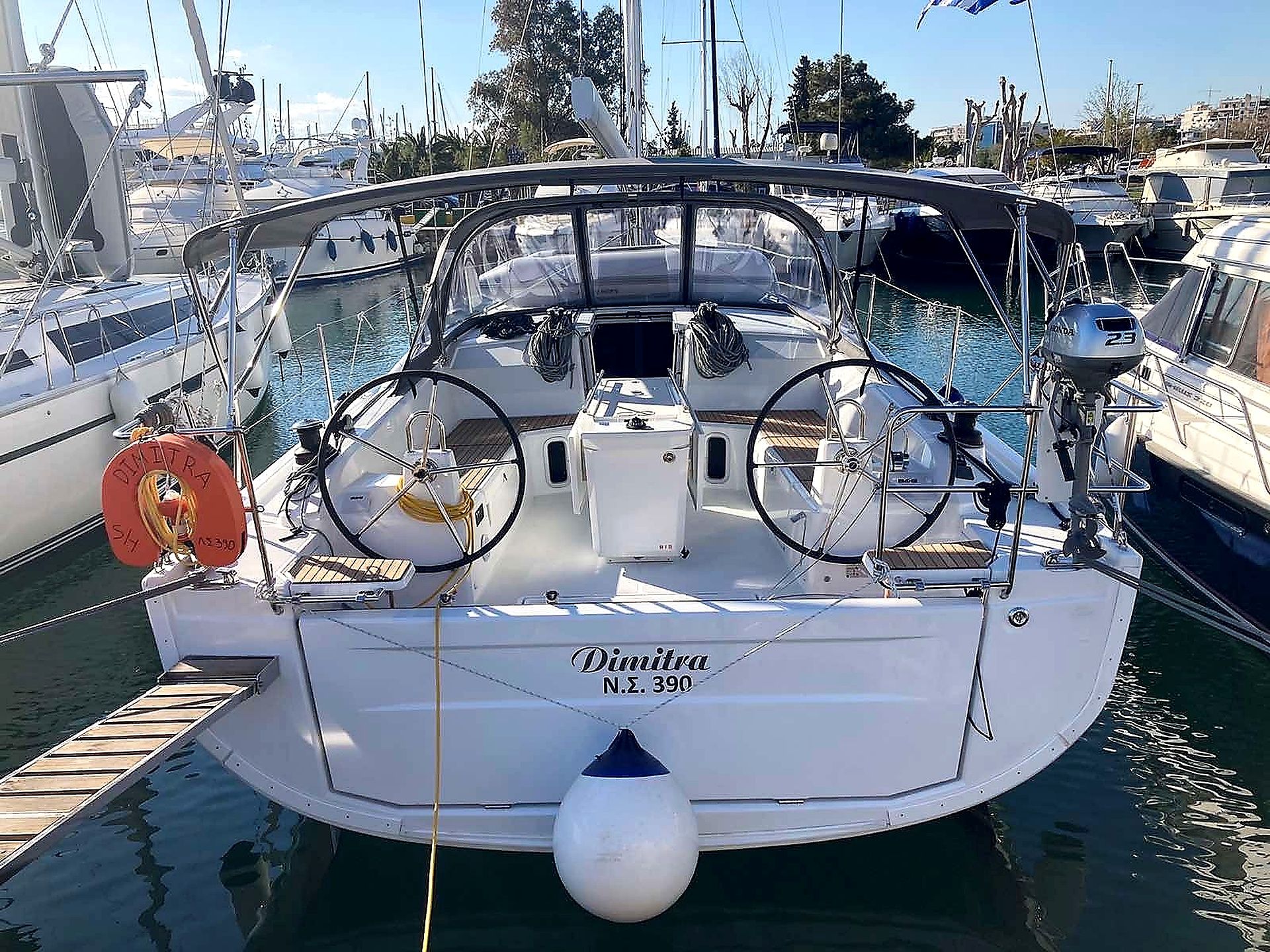 A yacht named 'Dimitra N.S. 390' docked at a marina with other boats, a lifebuoy, and a winch visible.