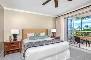 A hotel room with a bed, two bedside tables, a chair, a balcony with a view of palm trees and the ocean. - Honua Kai 3 Free Cars KBM Resorts Front Alii Suite 3 Units, 6 Bedrooms HK Ml-3161 (Kaanapali)