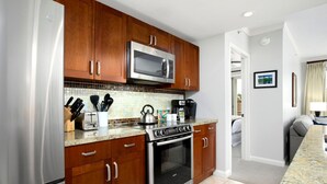A modern kitchen with wooden cabinets, stainless steel appliances, and a tiled backsplash. - Honua Kai 4 Free Cars KBM Resorts Front Alii Suite 4 Units, 8 Bedrooms HK Ml-3182 (Kaanapali)
