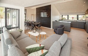 A modern living room with a sofa, coffee table, and dining area. - Pet friendly home in Sæby with sauna (Sæby)