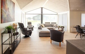 A modern living room with a sectional sofa, two recliners, a coffee table, and a dining area with chairs. - Pet friendly home in Sæby with sauna (Sæby)