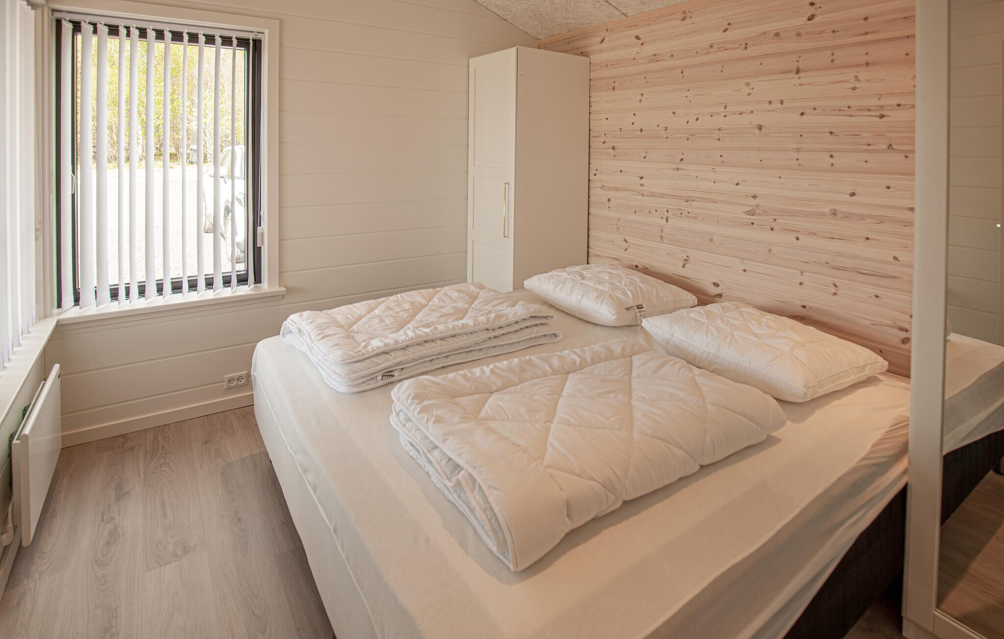 Een slaapkamer met een bed, een kledingkast en een raam met zonwering.