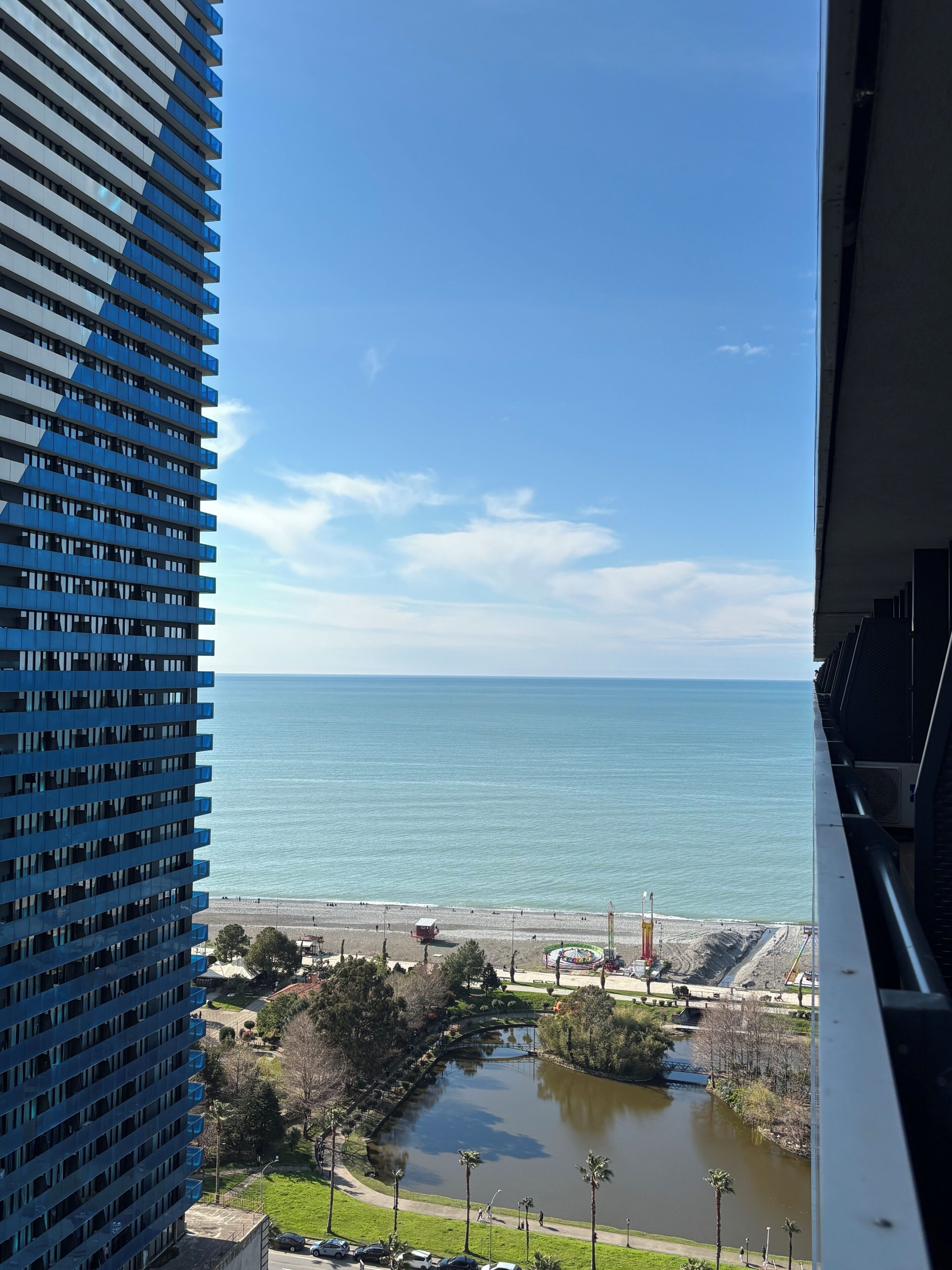 A high-rise building with a view of a beach and a lake.