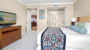 Hotelkamer met een bed, een televisie op een houten dressoir, een plafondventilator en een badkamer door een open deur zichtbaar.